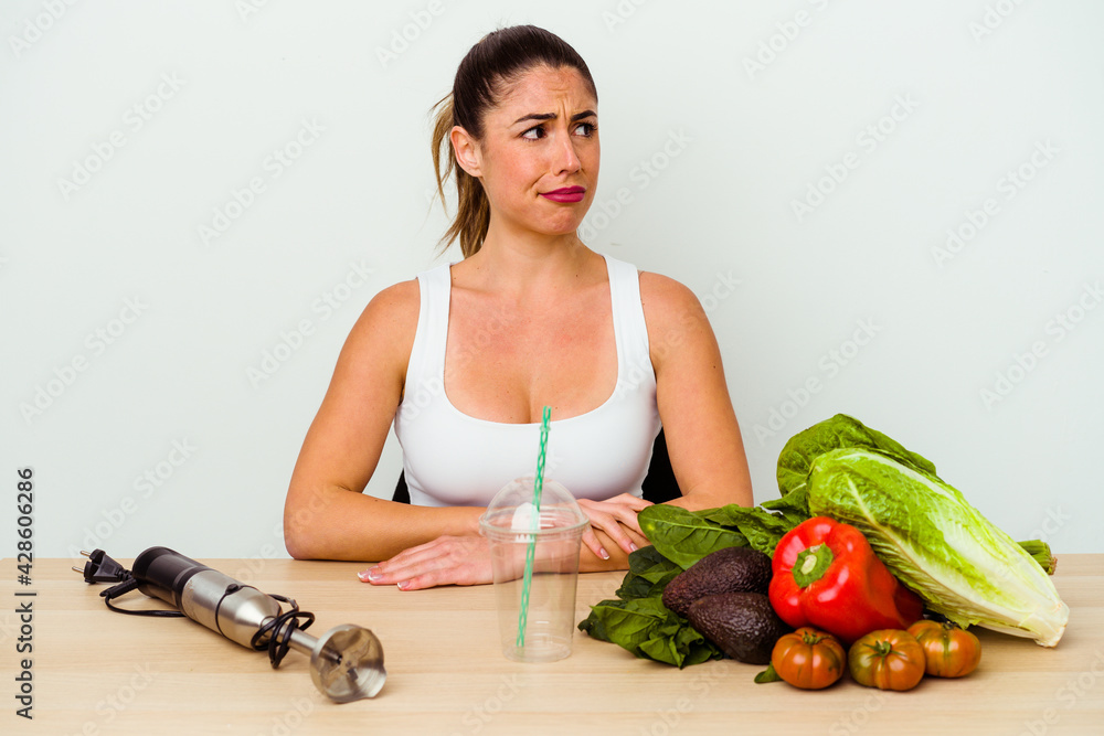 Young caucasian woman preparing a healthy smoothie with vegetables Young caucasian woman preparing a healthy smoothie with vegetables