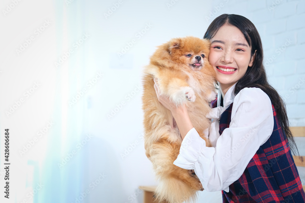 Beautiful young asian woman holding and hugging her dog in the room, Adorable asian woman smiling in blue and red seamless tartan plaid pattern shirt with dog.