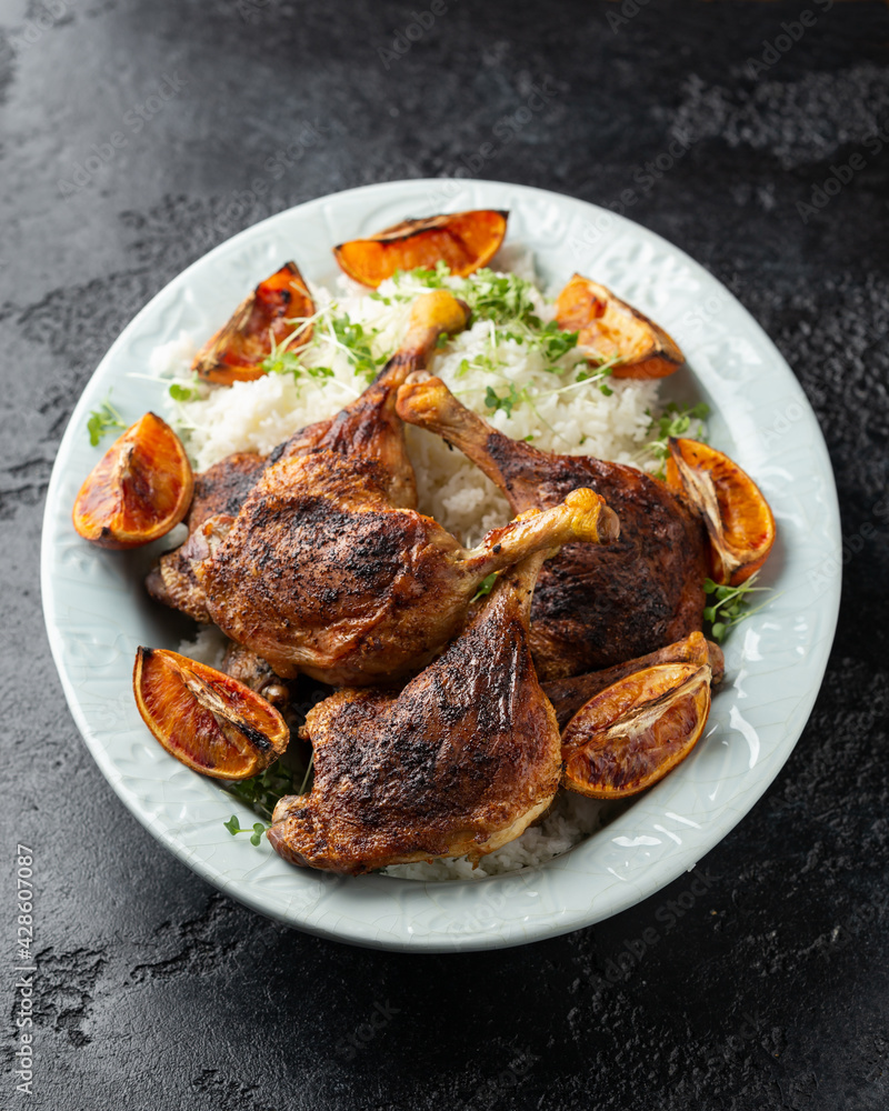 Slow cooked aromatic duck legs with basmati rice and side salad served with orange wedges. Slow cooked aromatic duck legs with basmati rice and side salad served with orange wedges.