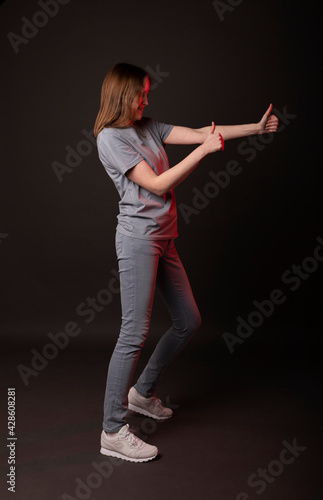 Young white woman showing thumb upin casual clothes, jeans on black background. photo