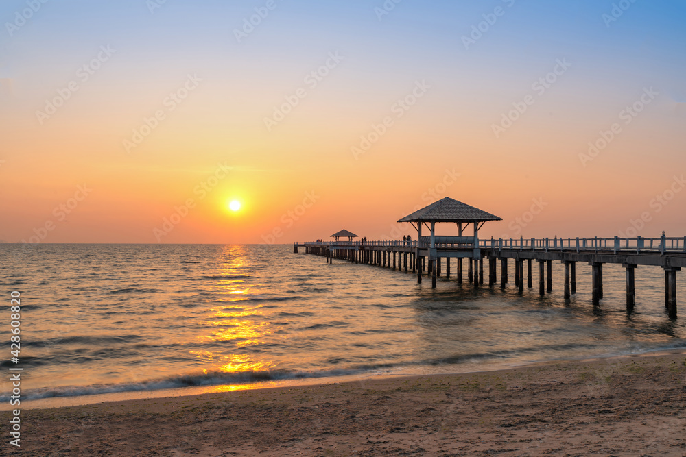 A wooden bridge in the sea with a sunset view