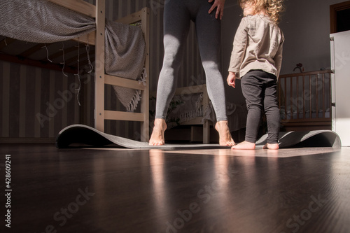 mom and little daughter play sports at home. yoga with a child at home