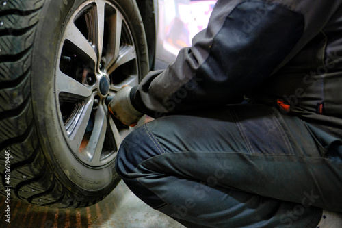 A mechanic uses a pneumatic wrench to change wheels in a tire replacement service center.