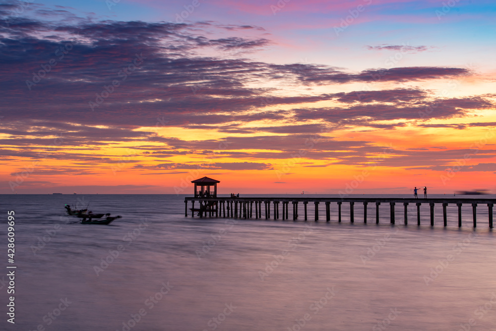 A wooden bridge in the sea with a  sky sunset  view
