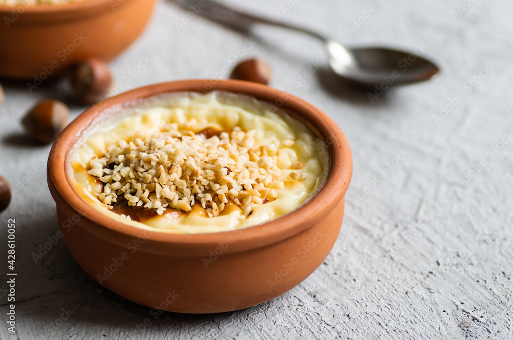 Baked rice pudding turkish milky dessert sutlac in casserole with cinnamon sticks and chopped hazelnuts Baked rice pudding turkish milky dessert sutlac in casserole with cinnamon sticks and chopped hazelnuts