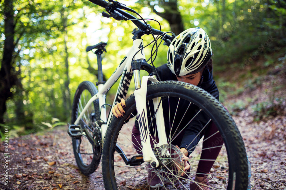 Fototapeta premium Woman repairs a bicycle in the woods