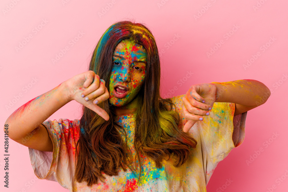 Young Indian woman celebrating holy festival isolated on white background showing thumb down and expressing dislike. Young Indian woman celebrating holy festival isolated on white background showing thumb down and expressing dislike.