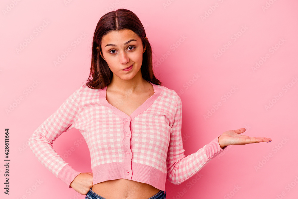 Young Indian woman isolated on pink background doubting and shrugging shoulders in questioning gesture. Young Indian woman isolated on pink background doubting and shrugging shoulders in questioning gesture.