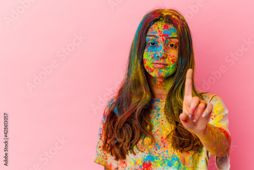 Young Indian woman celebrating holy festival isolated on white background showing number one with finger.