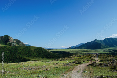 Travel across Altai. Dad with children in the fields against the background of mountains.