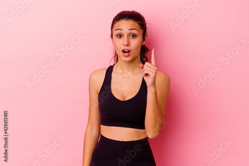 Young sport Indian woman isolated on pink background having an idea  inspiration concept.