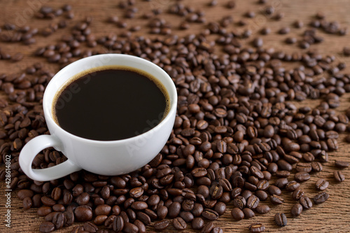 Black coffee and coffee beans roasted on wooden background copy space.