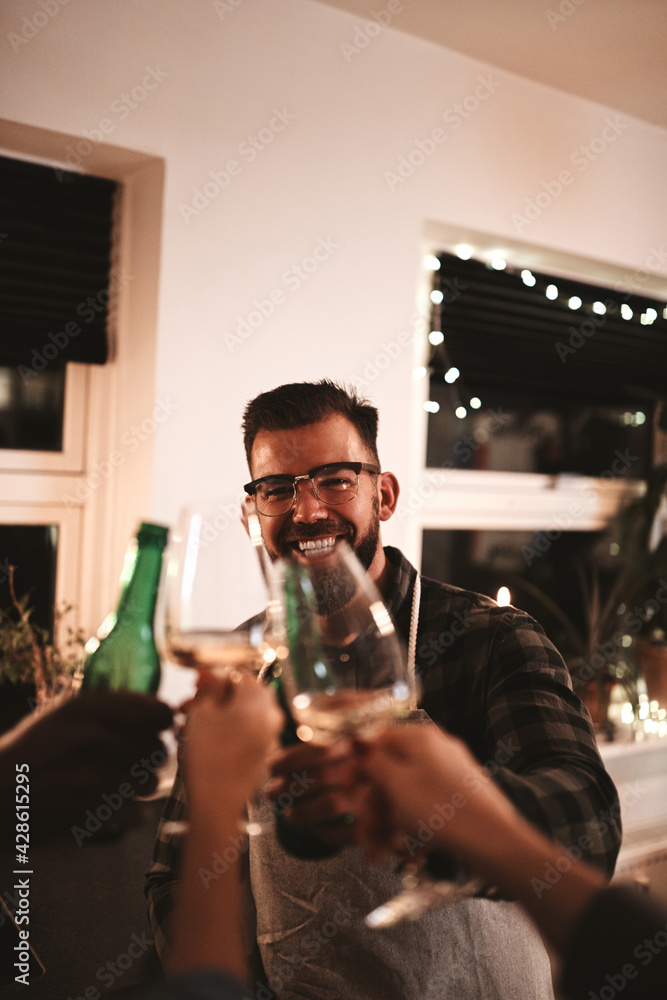 Laughing young man toasting his friends during a dinner party