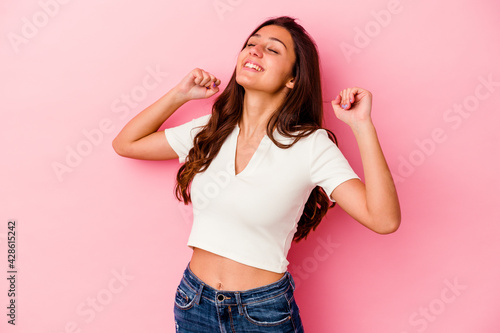 Young Indian woman isolated on pink background celebrating a special day, jumps and raise arms with energy.