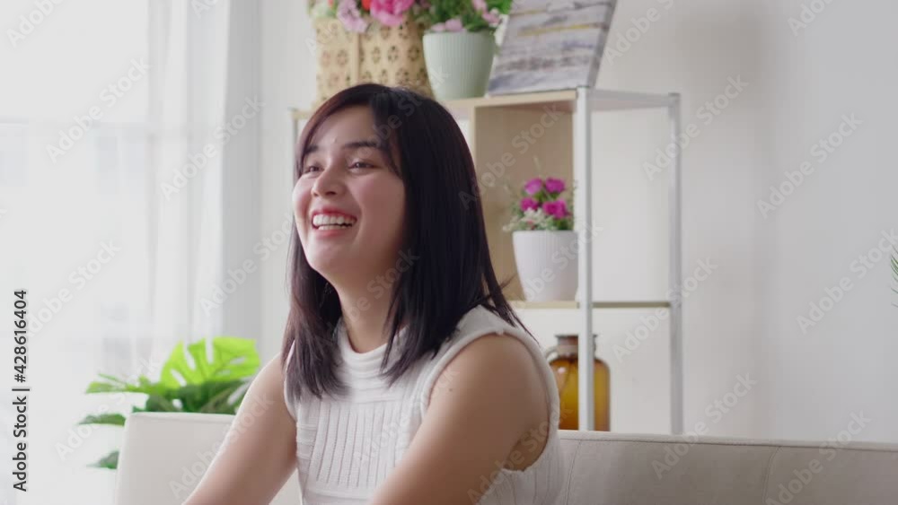 Asian woman happy laughing on indoor sofa at home in casual dress on morning. New actress model fail acting in sad scene but make laugh moment on camera Asian woman happy laughing on indoor sofa at home in casual dress on morning. New actress model fail acting in sad scene but make laugh moment on camera