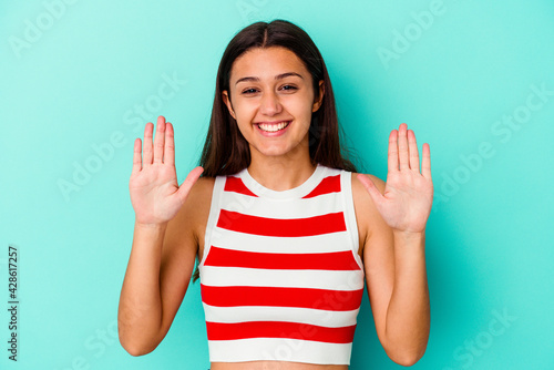 Young Indian woman isolated on blue background receiving a pleasant surprise, excited and raising hands.