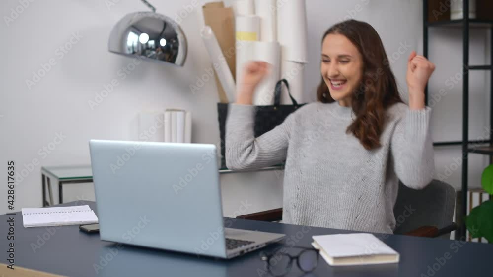 Overjoyed young woman surprised victory looks at the laptop sitting in the office, female celebrates good news received by email, got a job offer, amazed woman rejoice win in an online lottery Overjoyed young woman surprised victory looks at the laptop sitting in the office, female celebrates good news received by email, got a job offer, amazed woman rejoice win in an online lottery