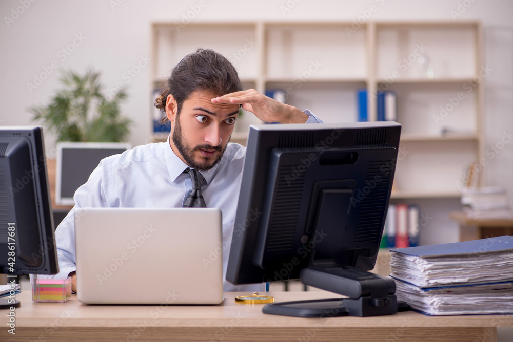 Young male employee in multitasking concept Young male employee in multitasking concept