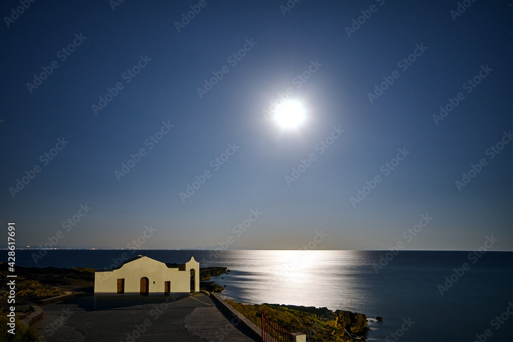 The facade of the Orthodox chapel illuminated by moonlight on the coast of the island of Zakynthos