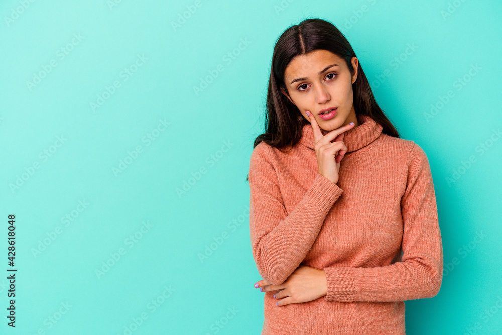 Young Indian woman isolated on blue background looking sideways with doubtful and skeptical expression. Young Indian woman isolated on blue background looking sideways with doubtful and skeptical expression.