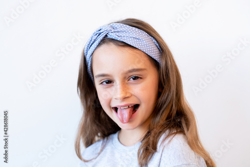 Playful kid portrait. Fun childhood. Positive lifestyle. Amused joyful happy cute smiling little girl teasing sticking tongue out isolated on white background.