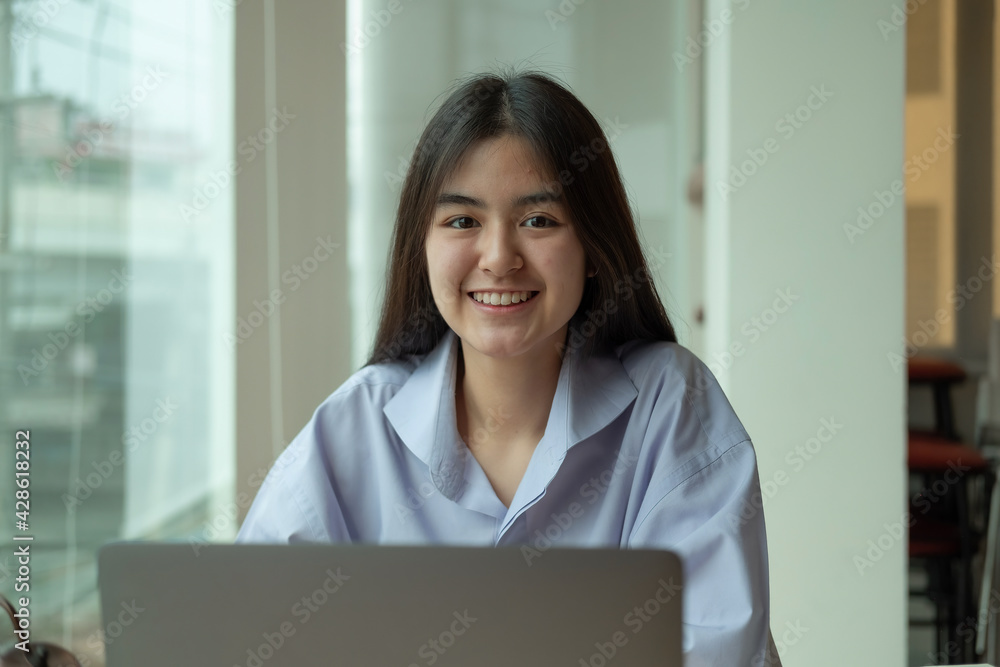 Portrait young asian girl looking camera while using laptop computer Portrait young asian girl looking camera while using laptop computer