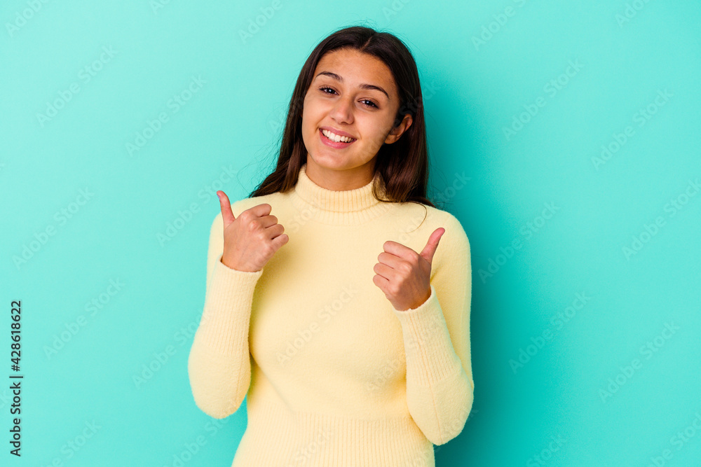 Young Indian woman isolated on blue background raising both thumbs up, smiling and confident. Young Indian woman isolated on blue background raising both thumbs up, smiling and confident.