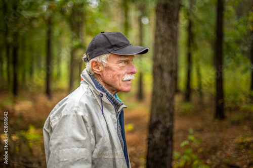 A mature man wearing a cap walking in the woods during the day. © toranote