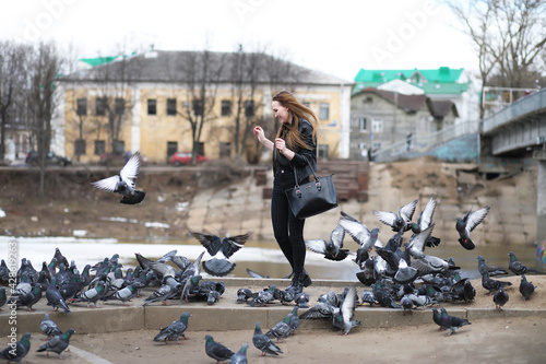 Girl on a walk in the park and a flock of pigeons