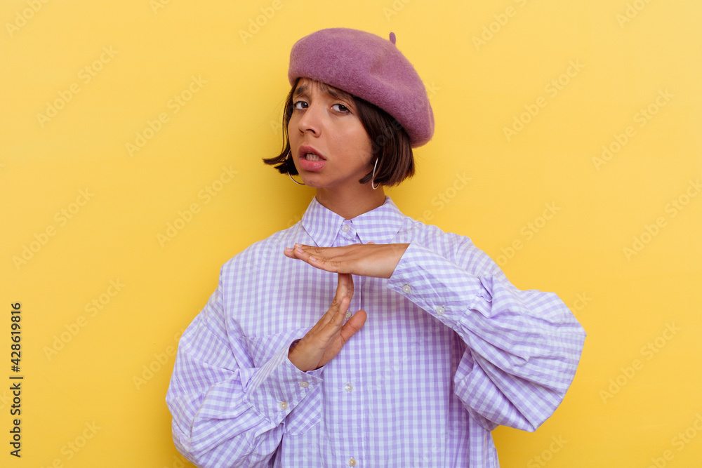 Young mixed race woman wearing a beret isolated on yellow background showing a timeout gesture. Young mixed race woman wearing a beret isolated on yellow background showing a timeout gesture.