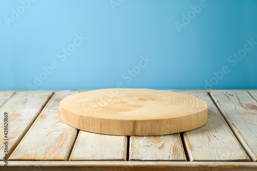 Fototapeta Naklejka Na Ścianę i Meble -  Empty wooden log on rustic table over blue wall  background.  Kitchen mock up for design and product display.