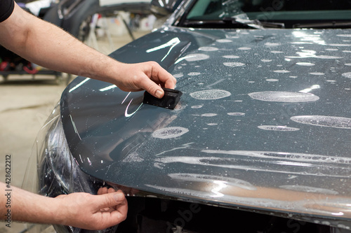 Installation of a protective paint and varnish transparent film on the car. PPF polyurethane film to protect the car paint from stones and scratches.