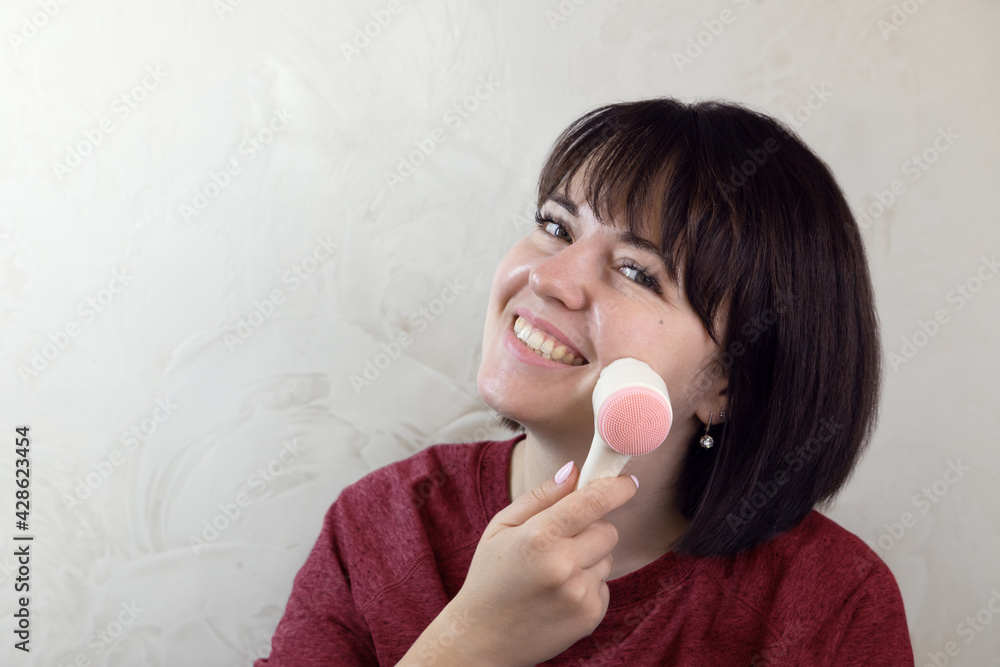 Young pretty woman doing facial massage with a brush. Close-up portrait, anti-aging facial massage at home, daily morning routine. Young pretty woman doing facial massage with a brush. Close-up portrait, anti-aging facial massage at home, daily morning routine.