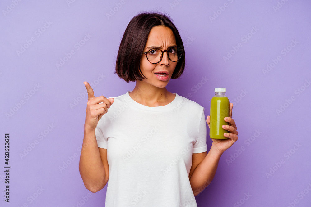 Young mixed race woman holding a healthy smoothie isolated on purple background having an idea, inspiration concept. Young mixed race woman holding a healthy smoothie isolated on purple background having an idea, inspiration concept.