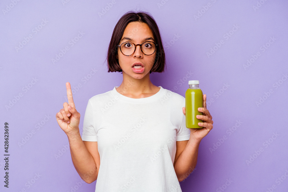 Young mixed race woman holding a healthy smoothie isolated on purple background having some great idea, concept of creativity. Young mixed race woman holding a healthy smoothie isolated on purple background having some great idea, concept of creativity.