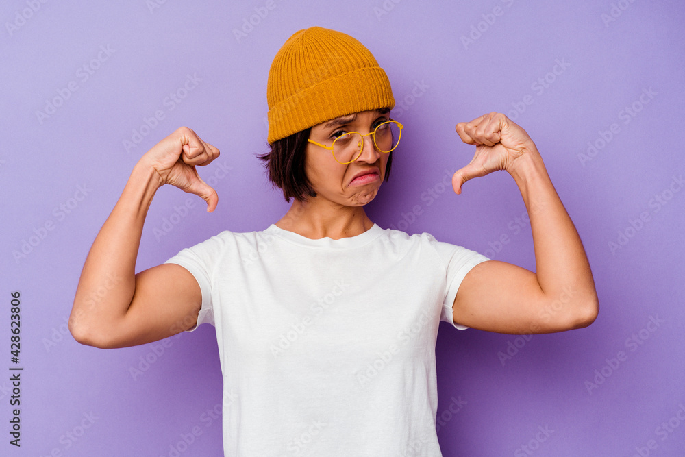 Young mixed race woman wearing a wool cap isolated on purple background feels proud and self confident, example to follow. Young mixed race woman wearing a wool cap isolated on purple background feels proud and self confident, example to follow.