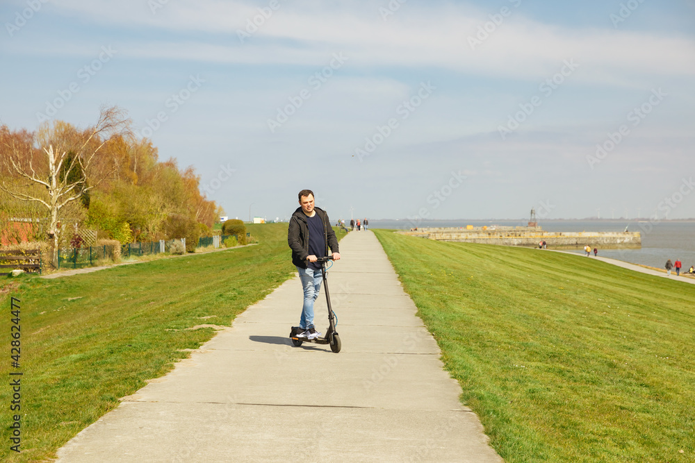 Man drives an electric scooter outside in a meadow Man drives an electric scooter outside in a meadow