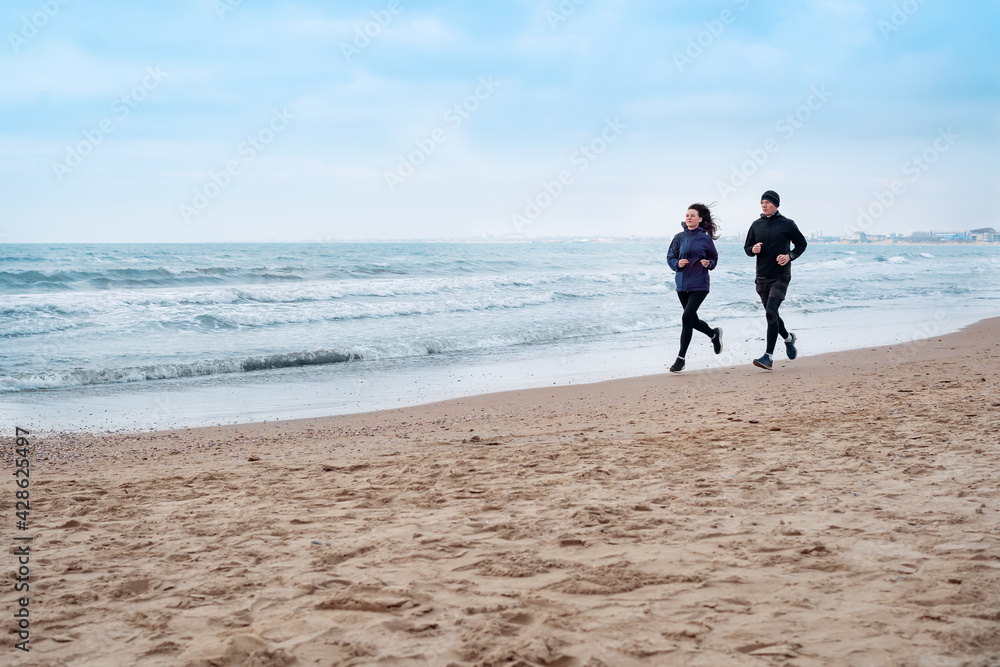 couple running along stone beach on morning