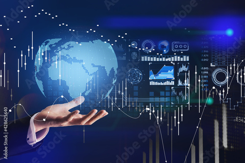 Businessman holding on his hand a globe projection. Stock market changes candlesticks, data information and digital interface. Concept of finance and technology.