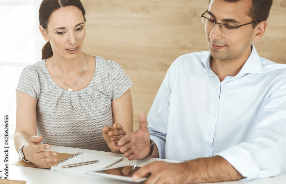 Businessman and hispanic business woman working with computer in a modern office. Group of diverse people. Teamwork, partnership and business concept Businessman and hispanic business woman working with computer in a modern office. Group of diverse people. Teamwork, partnership and business concept