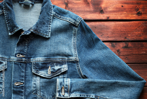 Giacca di jeans blu su fondo in legno. Direttamente sopra. Concetto di abbigliamento di moda. photo