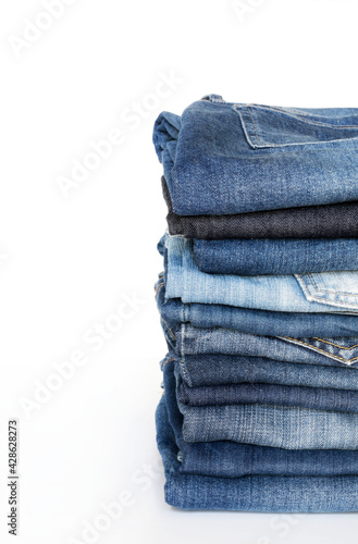 Pila di blue jeans isolati su sfondo bianco. Concetto di abbigliamento di moda. photo