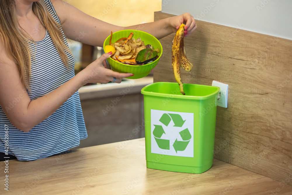 Responsible woman hands throwing away veg remains to the compost
