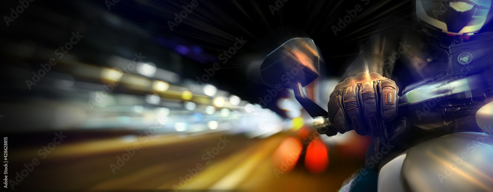 Motorbike biker with glove and full speed by night on city street with traffic and street lights.