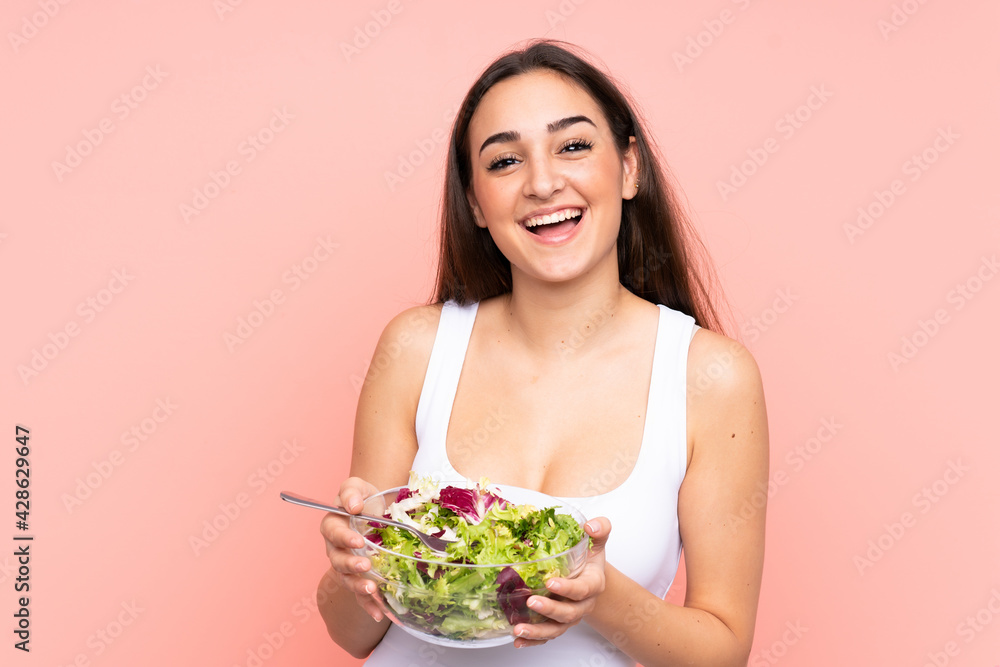 Young caucasian woman holding a salad isolated on pink background Young caucasian woman holding a salad isolated on pink background