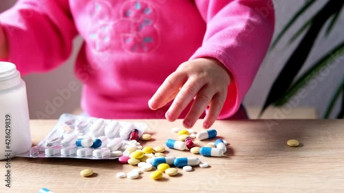 female hand of a small child, baby, girl playing with medical pills, hazardous to health, drug poisoning concept, poor babysitting photo