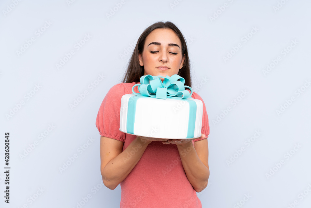 Pastry chef holding a big cake isolated on blue background Pastry chef holding a big cake isolated on blue background