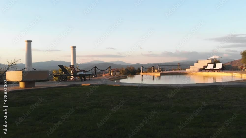 Revealing Flying Backwards Drone Shot at Sunset, Showing an Infinity Pool, Beautiful Garden that is Surrounded by the Spanish Andalucían Country Side with Mountains in the Background Revealing Flying Backwards Drone Shot at Sunset, Showing an Infinity Pool, Beautiful Garden that is Surrounded by the Spanish Andalucían Country Side with Mountains in the Background