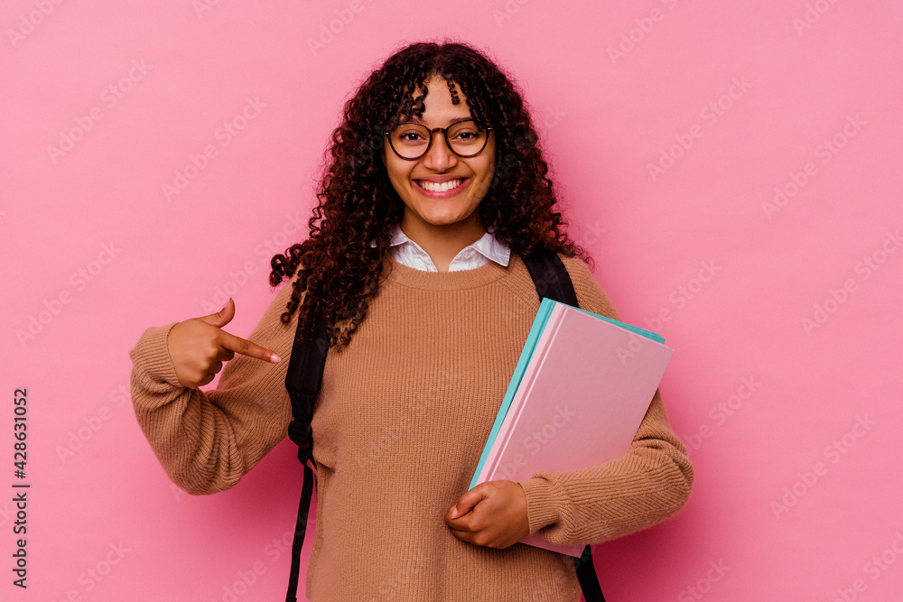 Young student mixed race woman isolated on pink background person pointing by hand to a shirt copy space, proud and confident Young student mixed race woman isolated on pink background person pointing by hand to a shirt copy space, proud and confident
