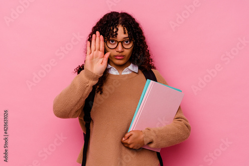 Young student mixed race woman isolated on pink background standing with outstretched hand showing stop sign, preventing you.